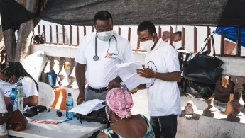 Zwei Ärzte sprechen mit einem Patienten in einem Camp für Vertriebene