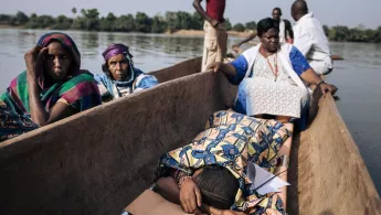 Mehrere Menschen in einem Kanu, eine Frau liegt auf einer Liege auf dem Boden