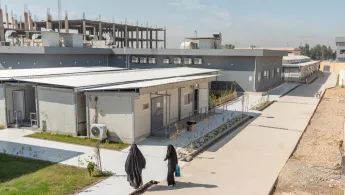 Der Krankenhauskomplex aus der Vogelperspektive mit zwei Frauen die auf den Eingang zu laufen