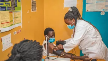 Eine Pflegekraft misst bei einem Patienten den Blutdruck