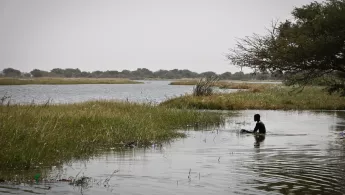 Mensch sitzt im Wasser am Ufer des Tschadsee