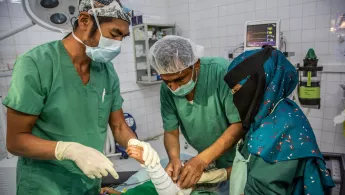 Operationsaal: Arzt und HelferInnen operieren.