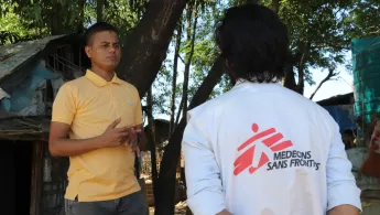 Mann in gelbem Polohemd spricht mit Mitarbeiter