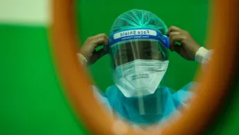 Eine medizinische Fachkraft passt den Gesichtsschutz an, bevor sie die Station betritt.