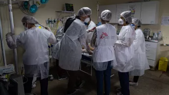 Medinisches Personal steht um ein Patientenbett, in dem ein Covid-19-Patient liegt.