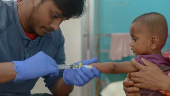 Ein Pfleger legt einen Zugang bei einem Kleinkind.