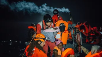 Rettung eines Säuglings aus einem Boot in Seenot.