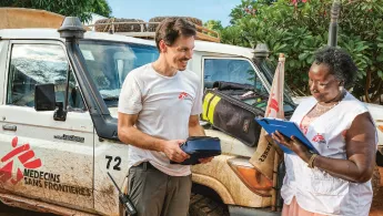 Zwei Mitarbeiter*innen kontollieren die Materialien für die mobile Klinik