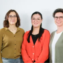 Die drei Ansprechpartnerinnen blicken in die Kamera und lächeln.