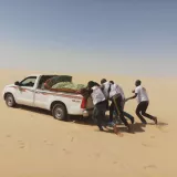 Unsere Mitarbeitenden schieben ein Auto in der Wüste an.