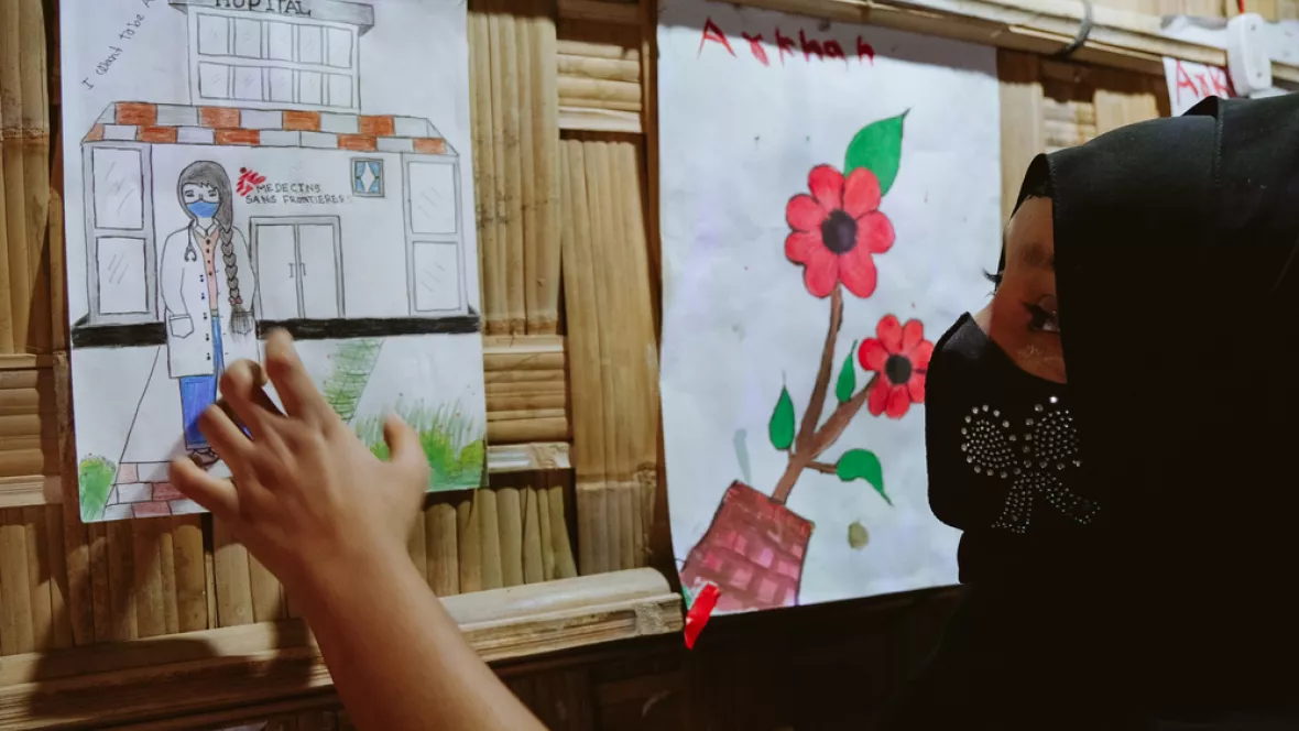Ein Mädchen zeigt auf ein selbst gemaltes Bild. Es zeigt eine Ärztin.