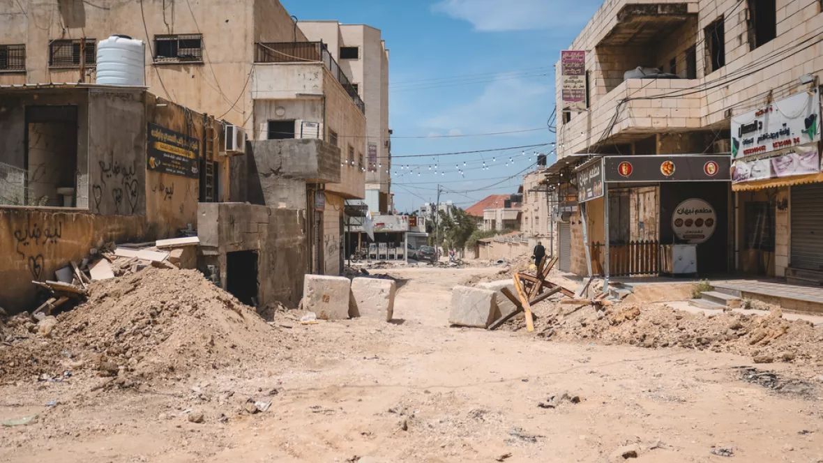Eine Straße samt Barrikade zwischen zerstörten Gebäuden