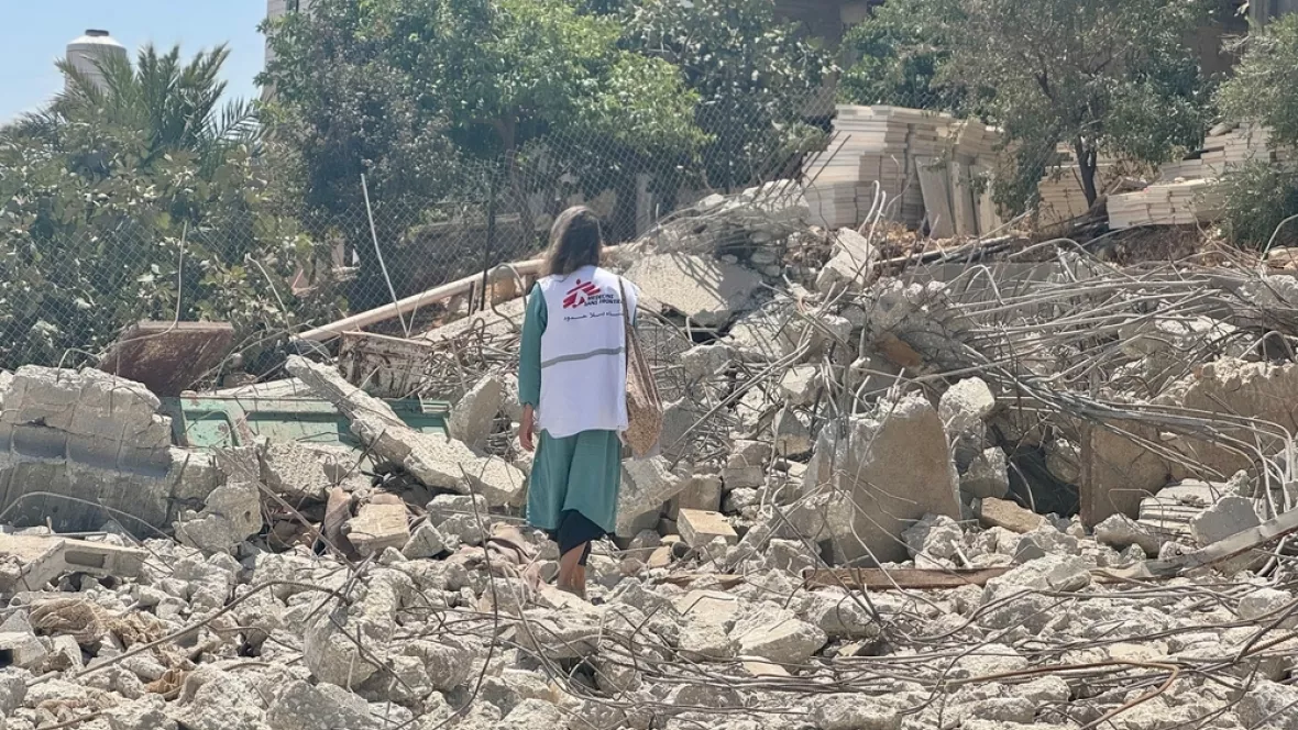 Eine Frau mit Weste mit dem Logo von Ärzte ohne Grenzen inmitten von Trümmern
