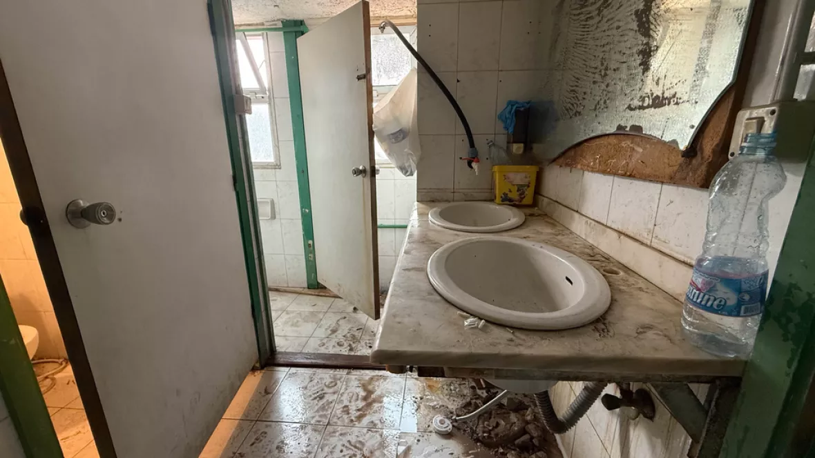 Ein Bad mit verschmutztem Boden, Spiegel und Toiletten sind zerstört..