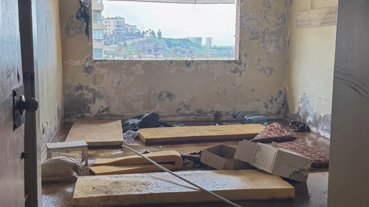 Ein Zimmer mit verschmutztem Boden und Matratzen, sowie baufälliger Decke und bröckelndem Putz an den Wänden.