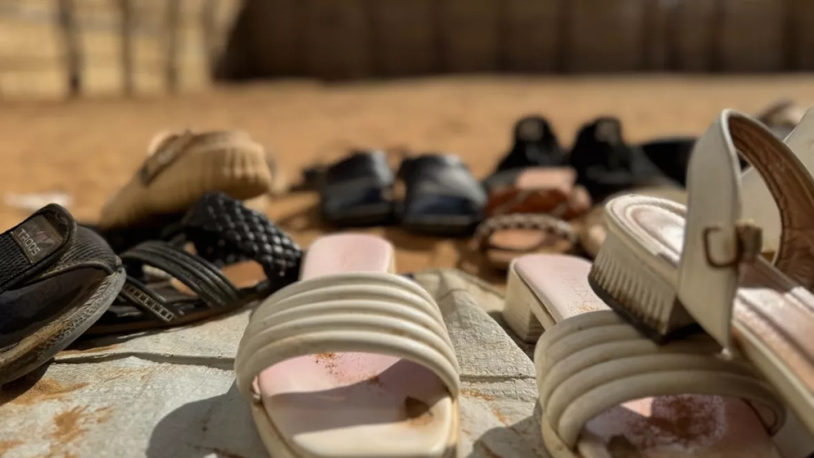 Mehrere Sandalen liegen im Sand auf dem Boden.