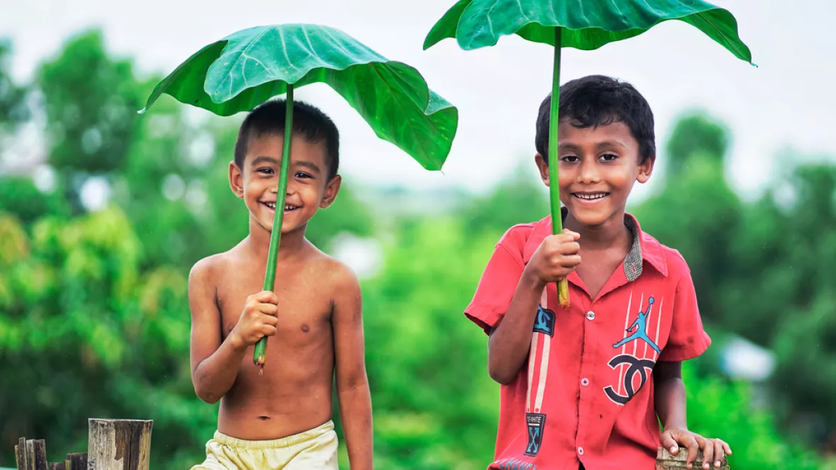 zwei kleine jungen halten Blätter wie Regenschirme über sich