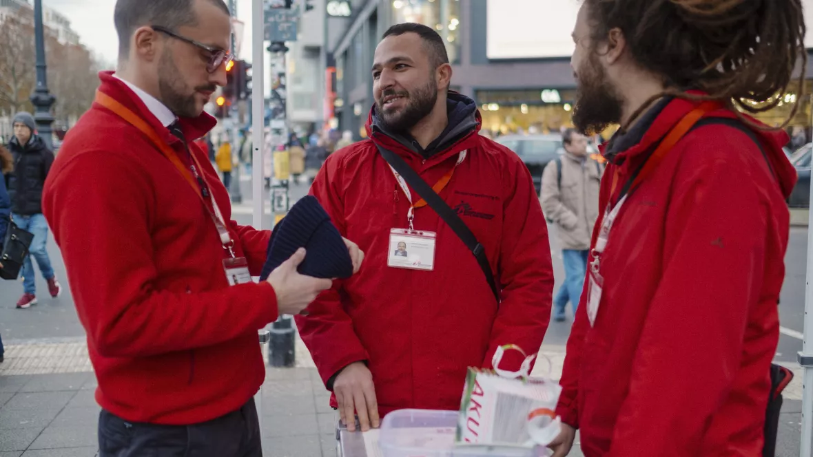 Drei Fundraising Mitarbeiter stehen auf der Straße und reden.