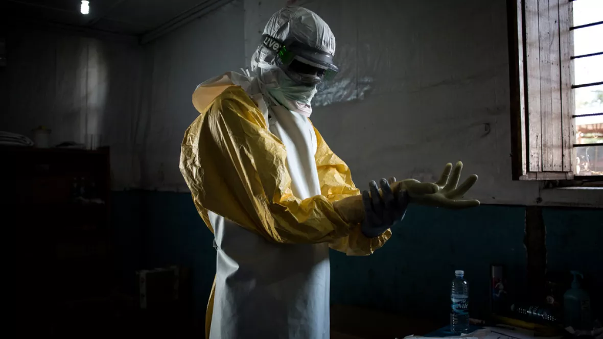 Ein Mitarbeiter zieht die äußeren Handschuhe der Ebola Schutzausstattung.
