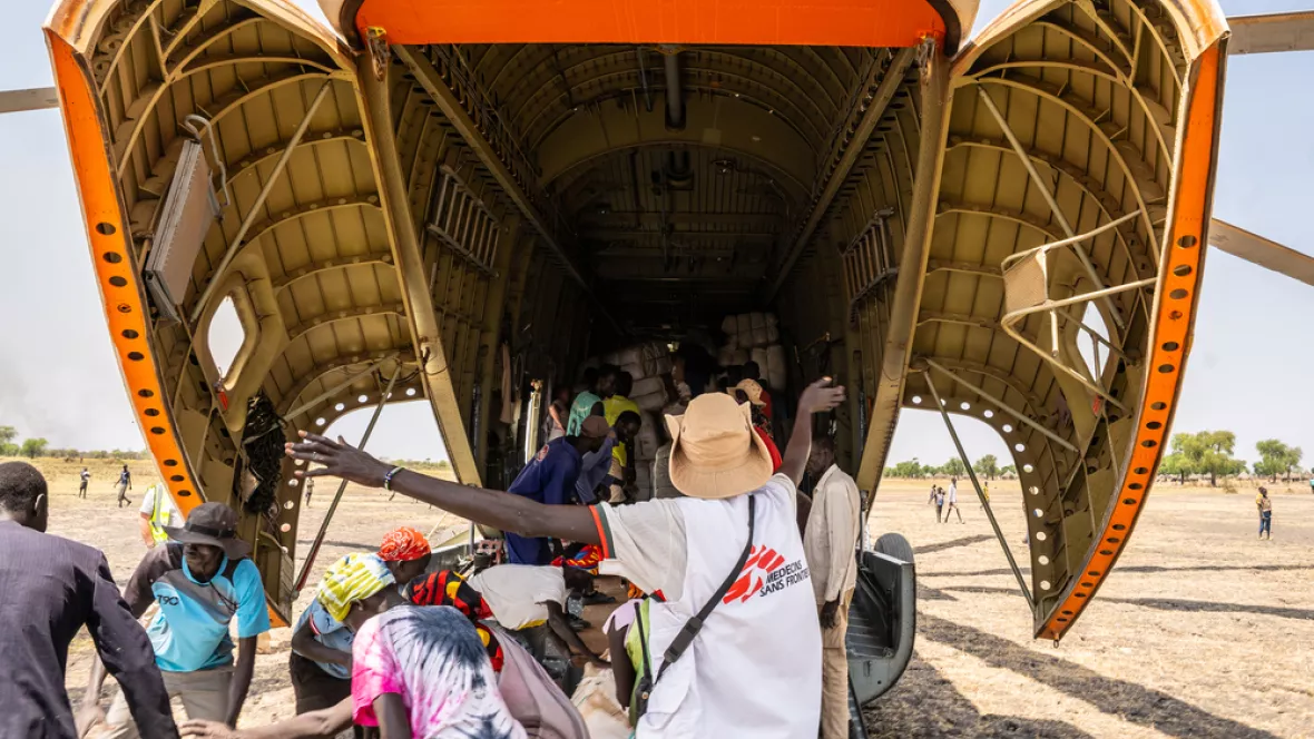 Ein Ärzte ohne Grenzen-Team und Helfende entladen Hilfsgüter aus einem Transportflugzeug auf einer Landepiste.