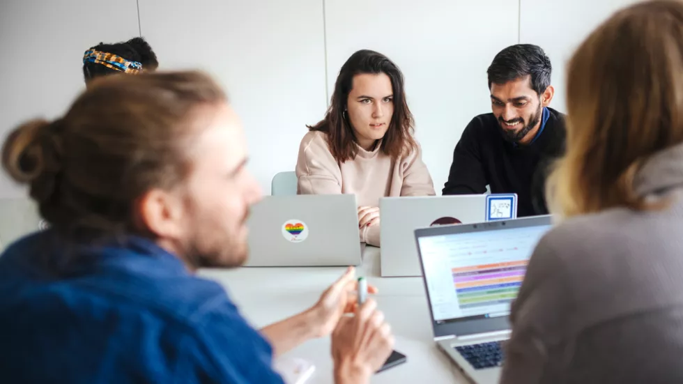 4 Personen mit Laptops sitzen um einen Tisch