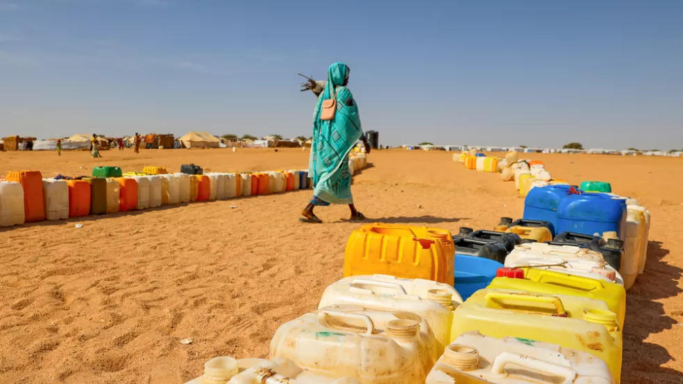 Frau läuft durch Reihe aufgestellter Wasserkanister