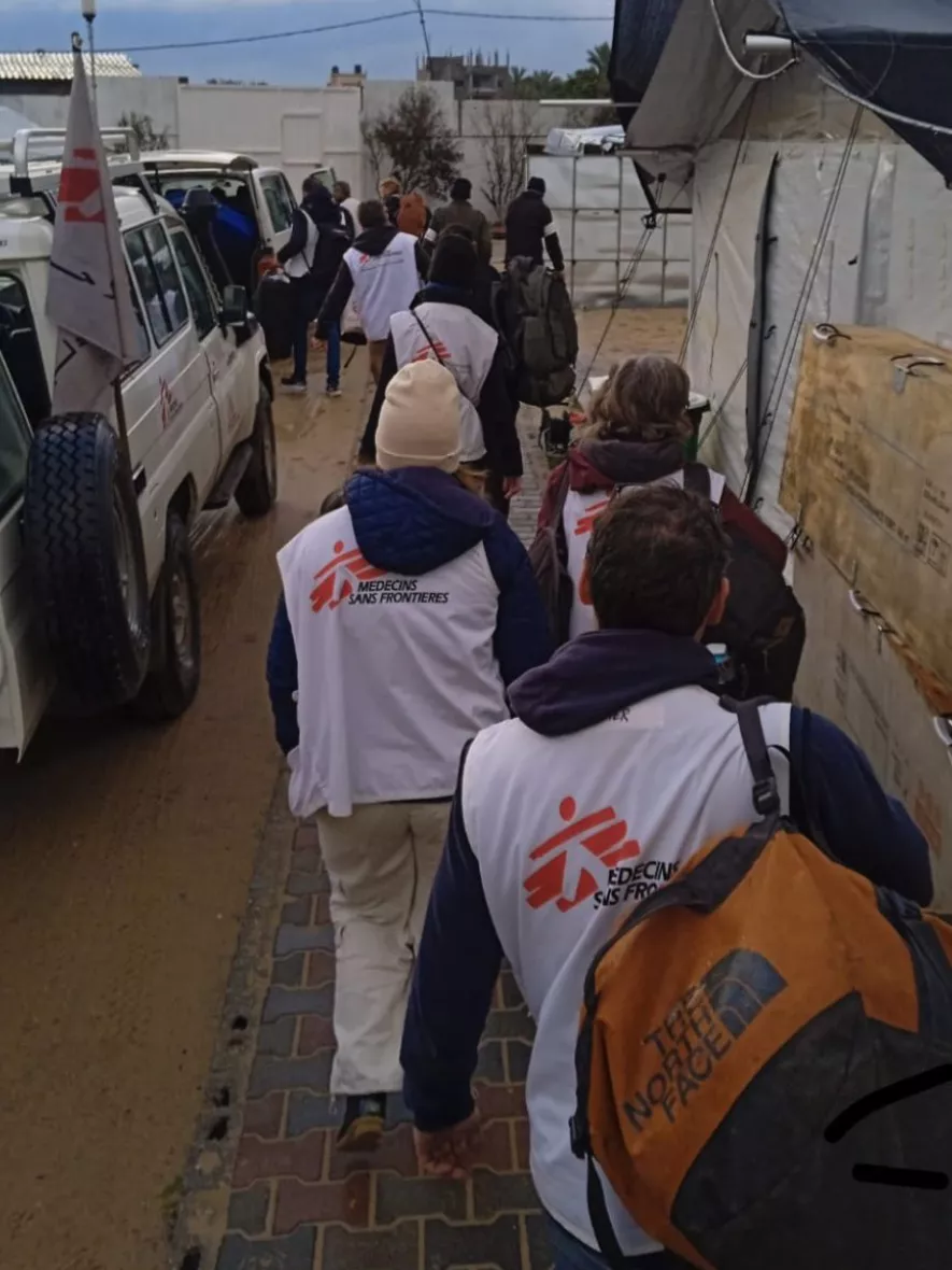 Mitarbeitende laufen mit Gepäck zu Fahrzeugen