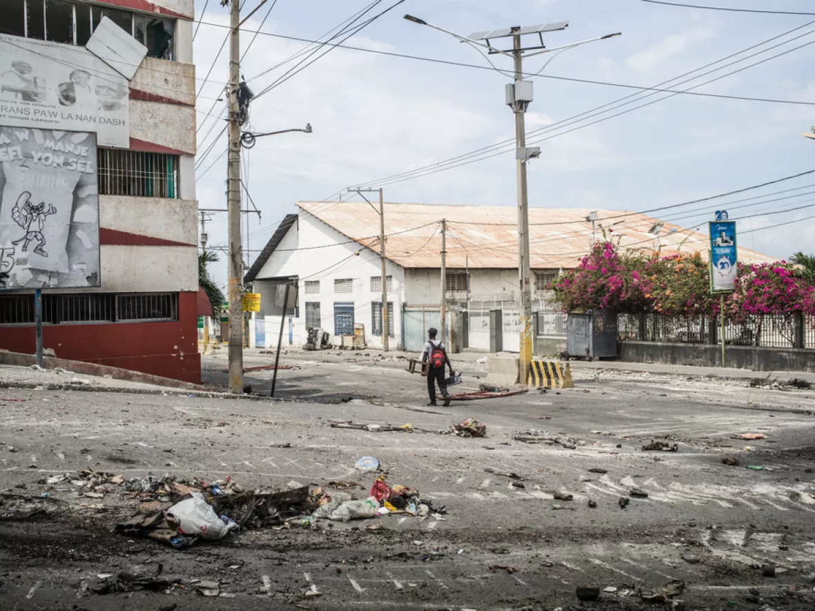 Ein Mensch läuft allein auf einer Straße, neben ihm Spuren der Zerstörung und Gewalt.