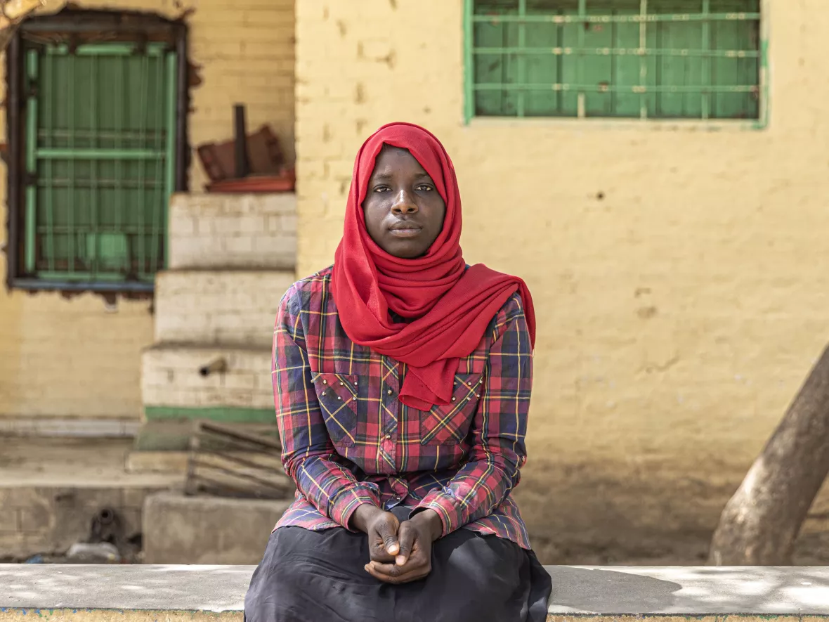 Portrait von Assma, die auf einer Mauer sitzt