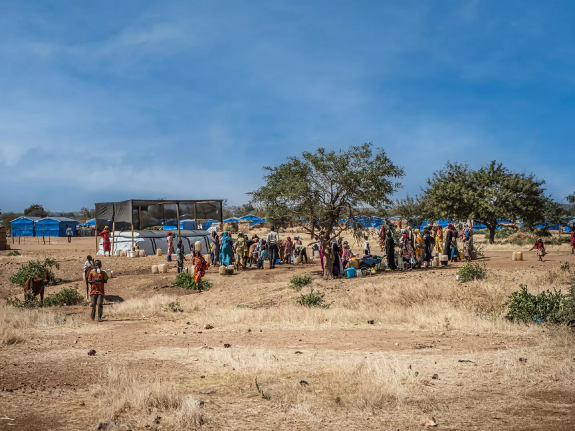 Menschen in Geflüchtetencamp stehen an Wasserverteilung an