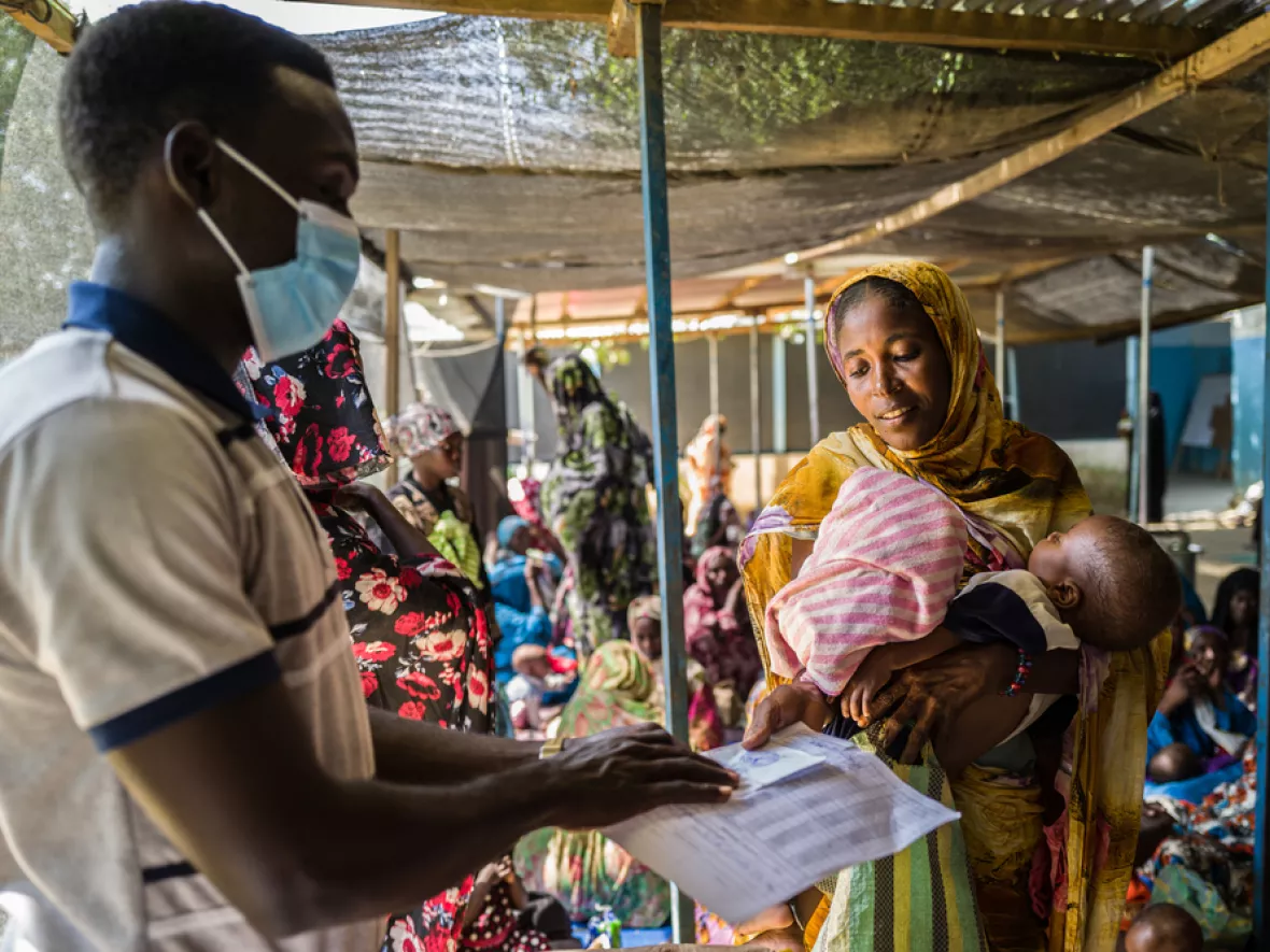 Frau mit Kind steht vor Mitarbeitendem