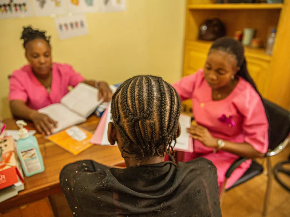 Zwei Mitarbeitende an Tisch im Gespräch mit Patientin