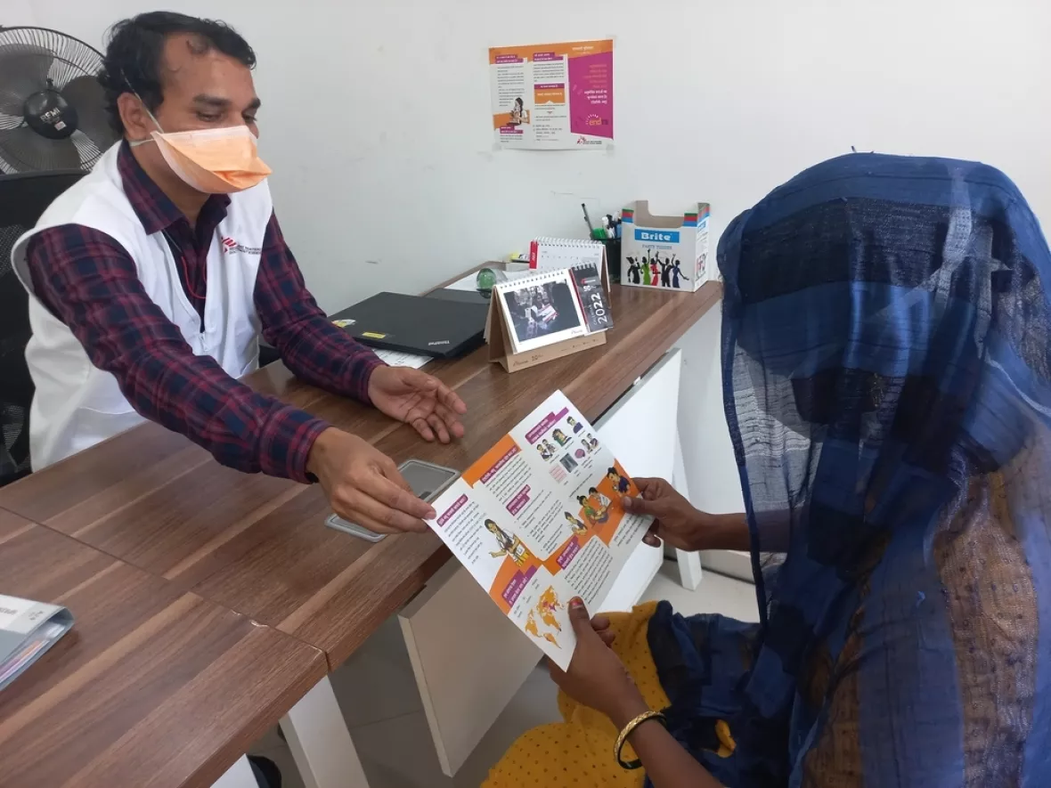 Unser Gesundheitsberater übergibt einer Patientin einen Flyer.