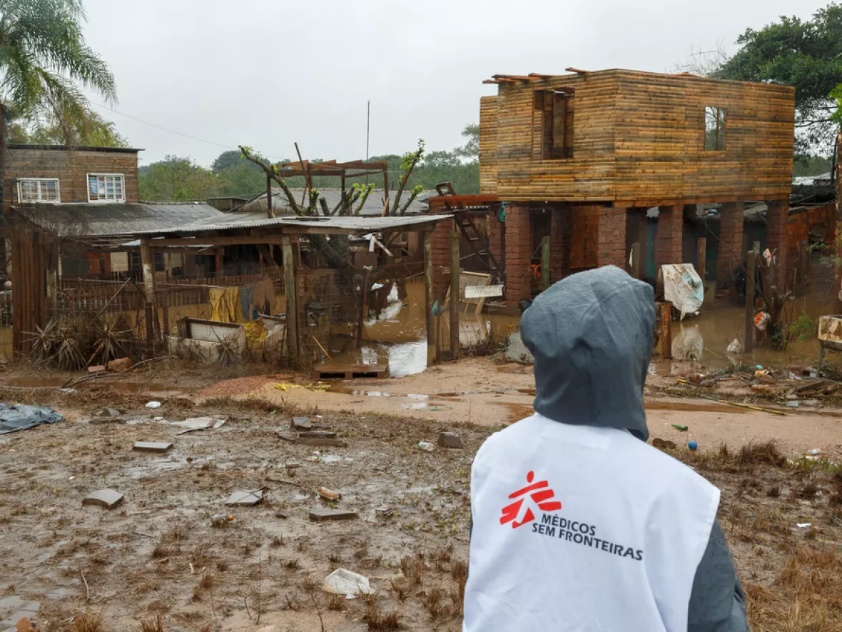 Mitarbeitende vor durch Überschwemmung zerstörten Gebäuden und Straßen
