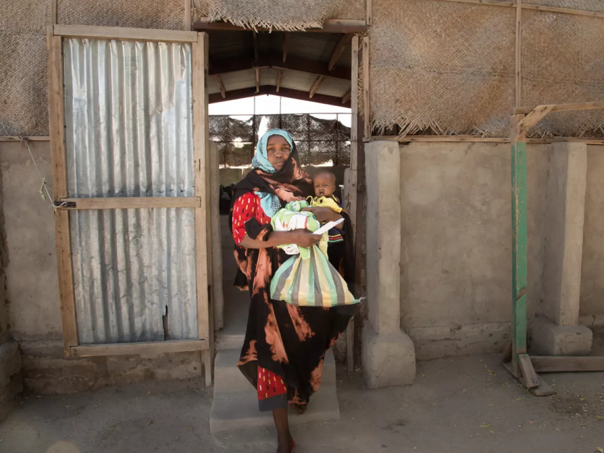 Mutter mit Kind auf dem Arm verlässt Gebäude