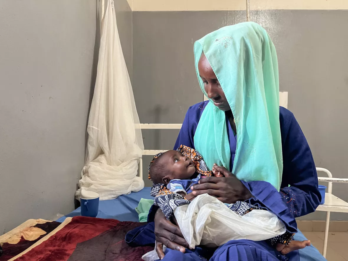 Mutter hält ihre Kind im Arm.