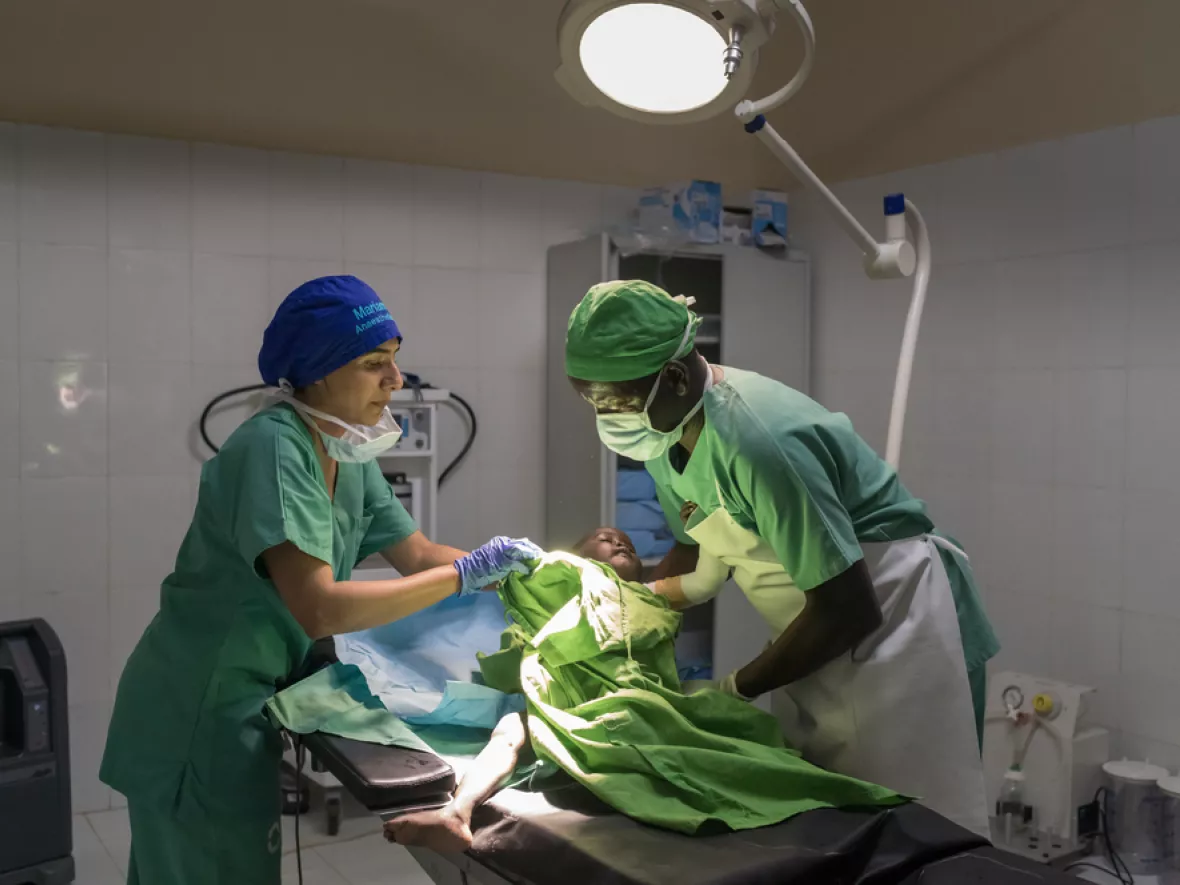 Zwei Mitarbeitende lagern Kind auf OP-Tisch