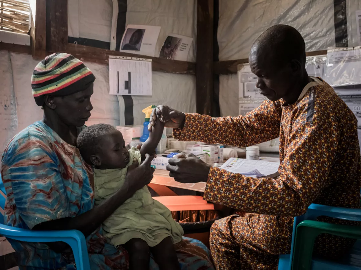 Frau mit Kleinkind sitzt gegenüber von Mitarbeiter für Untersuchung