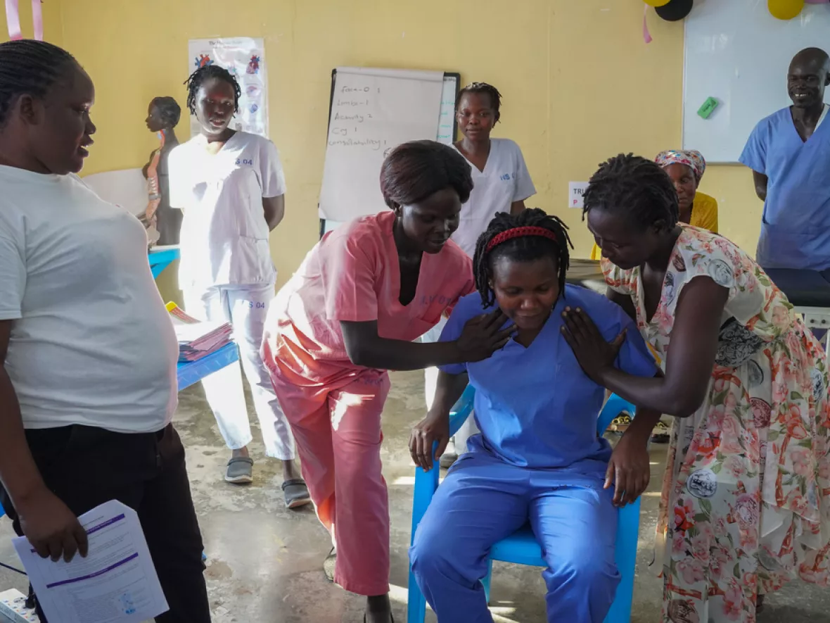 Mitarbeitende stellen Szenario sitzender Patientin nach, die bewegt wird