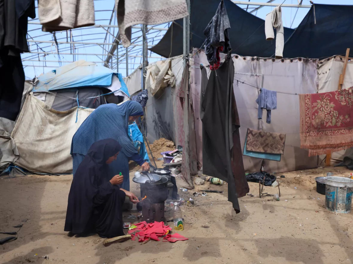 2 Frauen Kochen inmitten einer behelfsmäßigen Unterkunft.