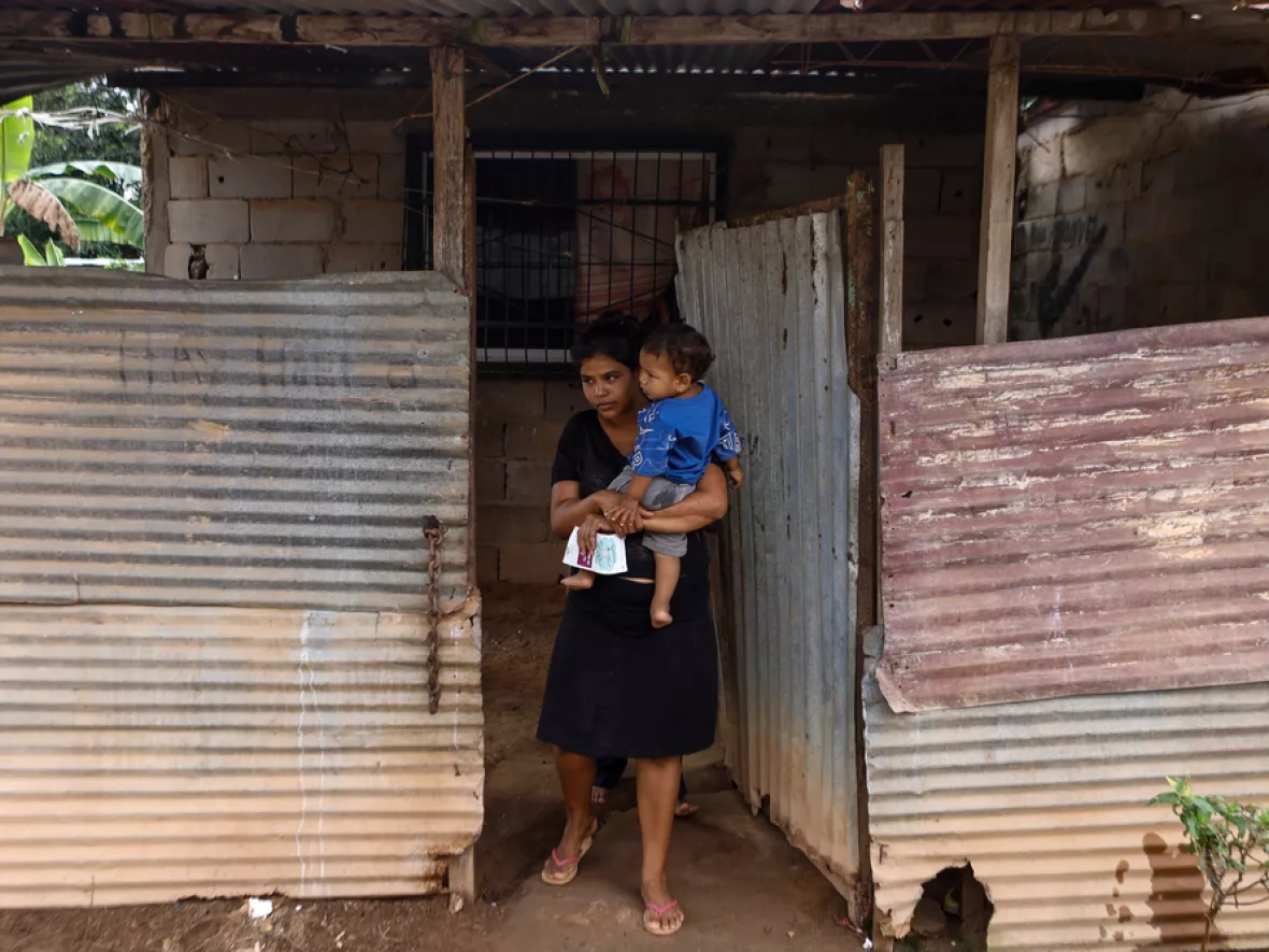 Frau mit Kind auf dem Arm vor ihrem Haus in Tumeremo, südliches Venezuela