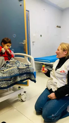 Mädchen im Bett bläst Seifenblasen, Psychologin kniet