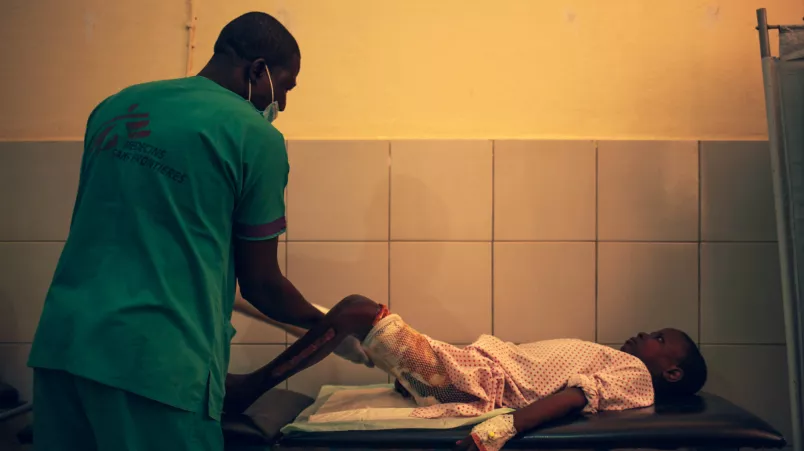 Ein Kind liegt auf einer Krankenliege und erhält Physiotherapie