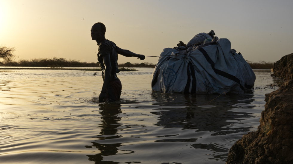 Ein Mann transportiert seine Habseligkeiten durch das Flutwasser 