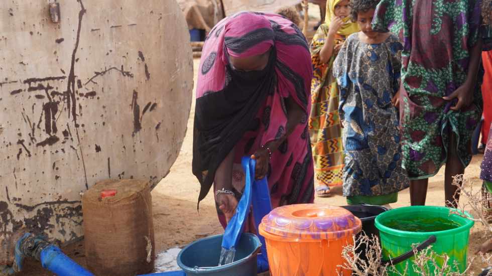 Eine Frau in Mali holt Trinkwasser aus einem Tank.