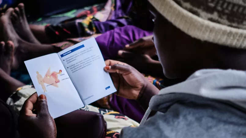 Ansicht auf ein Informationsheft über die Schulter einer Patientin