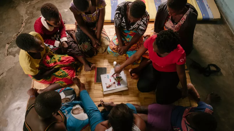 Eine Gruppe Frauen sitzt im Kreis, eine erklärt mit einer flip chart