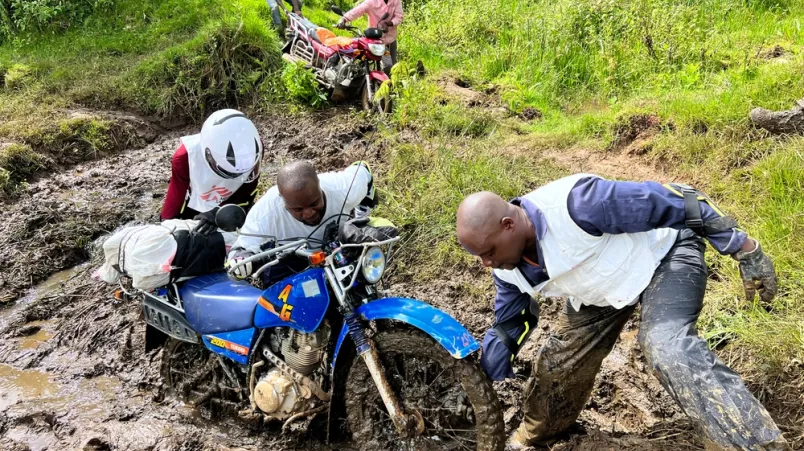 Mitarbeiter versuchen ein Motorrad aus dem Schlamm zu ziehen.