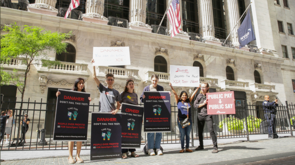 Aktivist*innen mit Plakaten: Cepheid soll Preis für GeneXpert-Tests für Tuberkulose senken