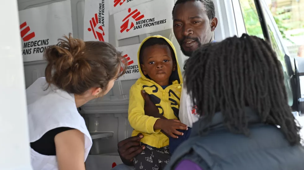 Mitarbeiterin untersucht Vater und Kind in Ventimiglia, Italien